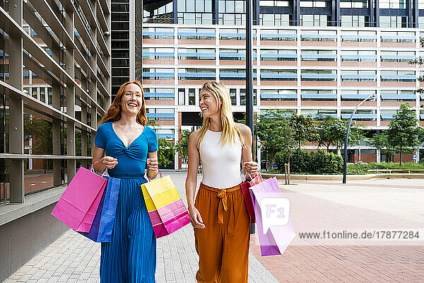 Smiling women carrying shopping bags outside mall