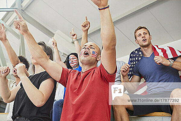 Fans mit Gesichtsbemalung rufen gemeinsam bei Sportveranstaltung im Stadion