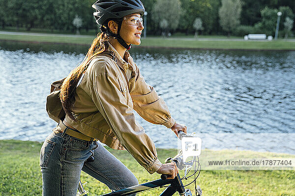 Woman riding bicycle by lake at park