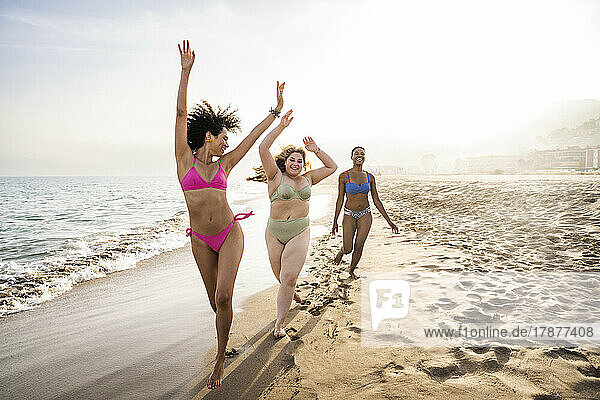Carefree multiracial friends enjoying on shore at beach
