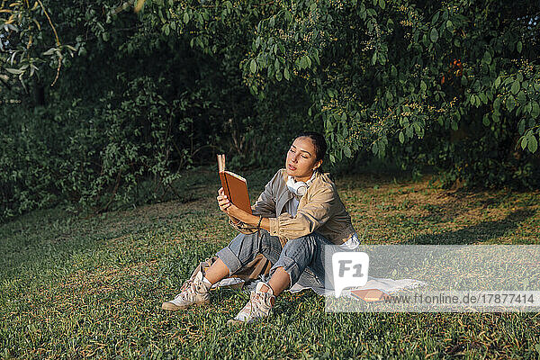 Woman reading book sitting on grass at park