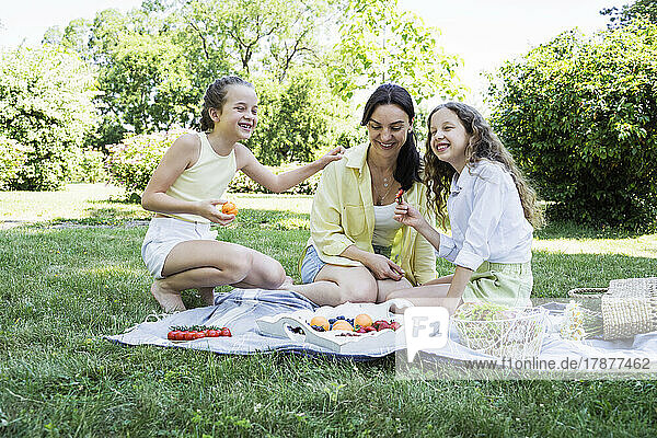 Happy daughters having picnic with mother at park on weekend