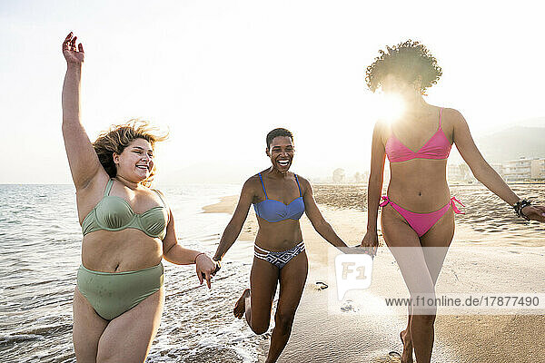 Carefree multiracial women having fun at beach on sunny day