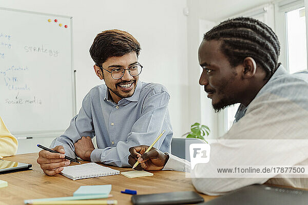 Smiling businessman talking with colleague at office