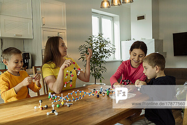 Mutter und Kinder mit molekularen Strukturen auf dem heimischen Tisch