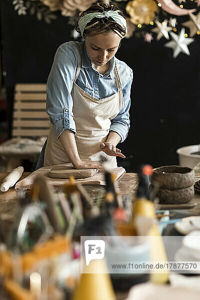 Potter kneading clay on workbench at art studio