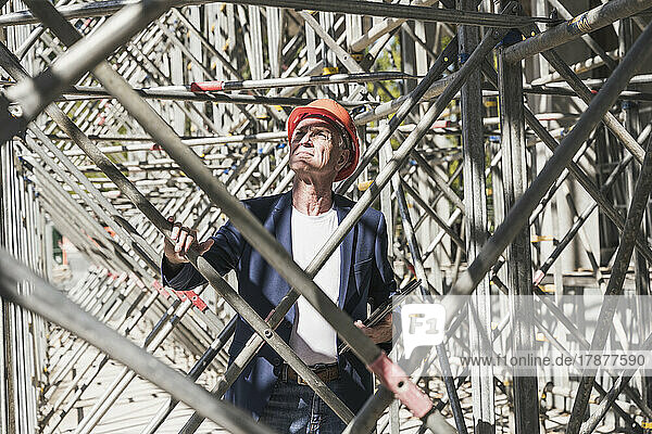 Engineer examining scaffolding at construction site on sunny day