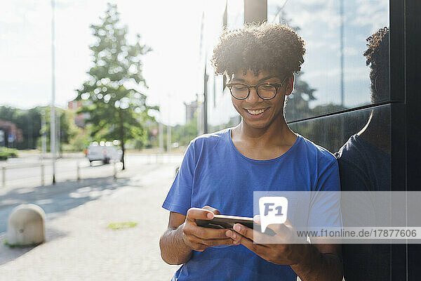 Lächelnder junger Mann  der ein Spiel auf dem Smartphone spielt