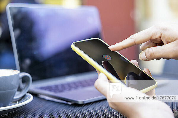 Hands of businesswoman turning off mobile phone at sidewalk cafe