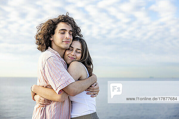 Happy young couple with eyes closed embracing each other