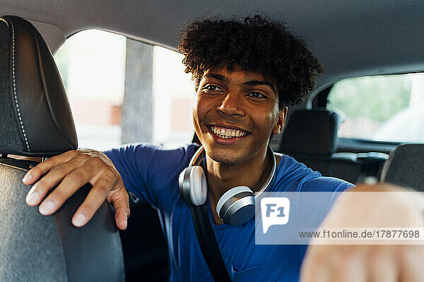 Smiling man with curly hair sitting in car