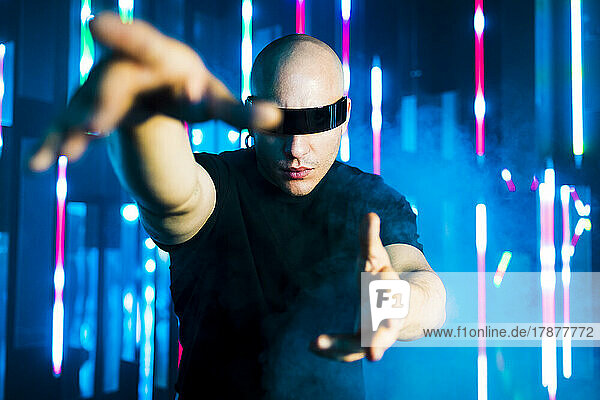 Man with smart glasses gesturing in front of illuminated lights