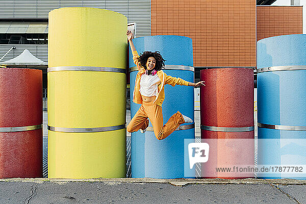 Happy woman jumping in front of colorful pipes