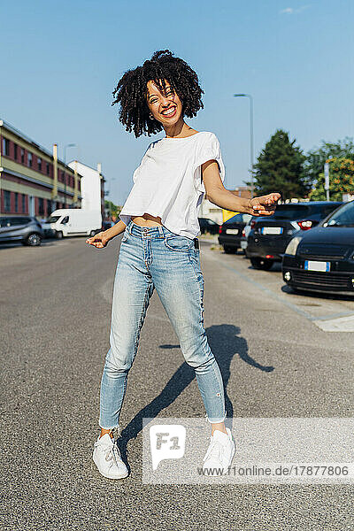 Happy young woman dancing on road