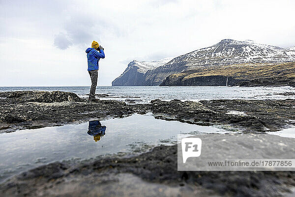 Faroe Islands  Eysturoy  Eidi  Male hiker photographing coastal landscape