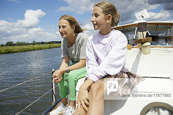 Senior woman and granddaughter sitting together on boat deck