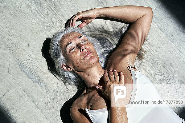 Reife Frau mit geschlossenen Augen und Hand auf der Brust  die im Sonnenlicht ruht