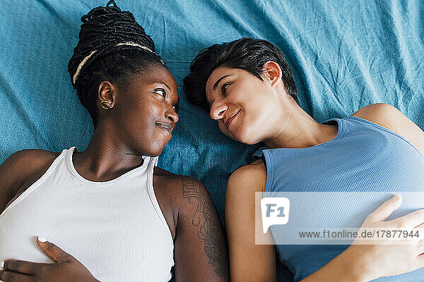 Smiling lesbian couple lying on bed