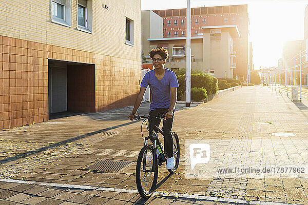 Smiling man cycling in city at sunset