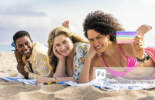 Woman taking selfie with friends through smart phone at beach