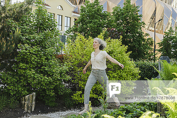 Carefree woman running by plants in park