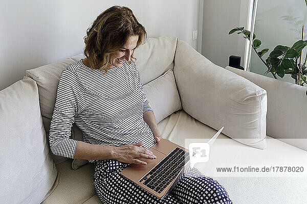 Lächelnde Frau  die zu Hause Laptop benutzt