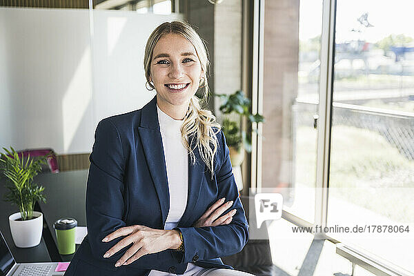 Happy businesswoman with arms crossed in office