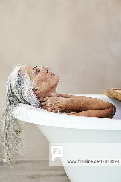 Woman taking bath in bathtub at home