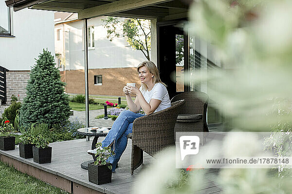 Smiling woman having coffee on porch