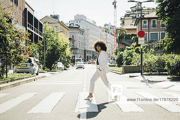 Young businesswoman crossing street on sunny day