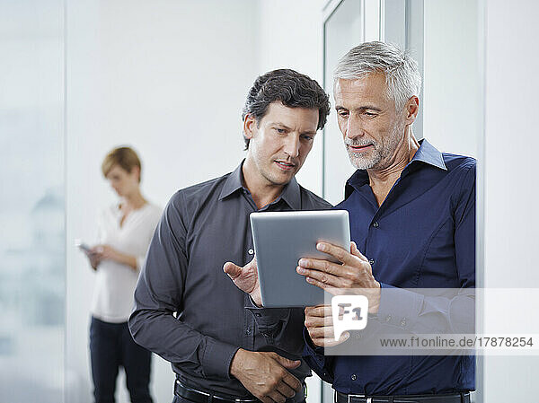Business colleagues discussing over tablet PC in office