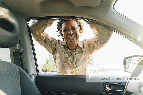 Happy young businesswoman looking through car window