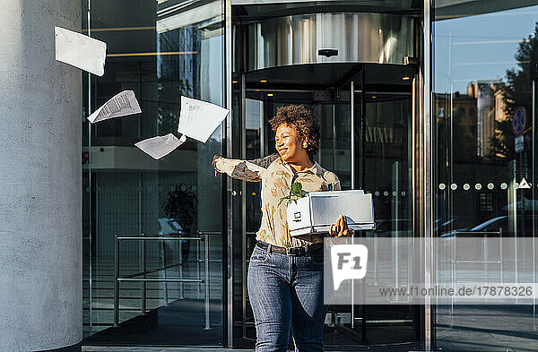 Glückliche Geschäftsfrau wirft Papiere vor der Tür weg