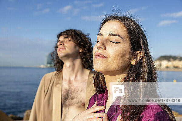 Young couple standing in eyes closed on sunny day