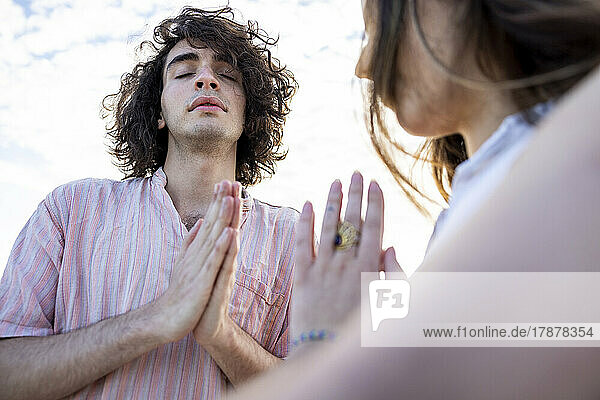 Junges Paar meditiert mit gefalteten Händen