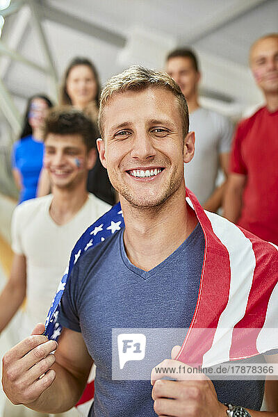 Smiling man holding American Flag in at sports event in stadium