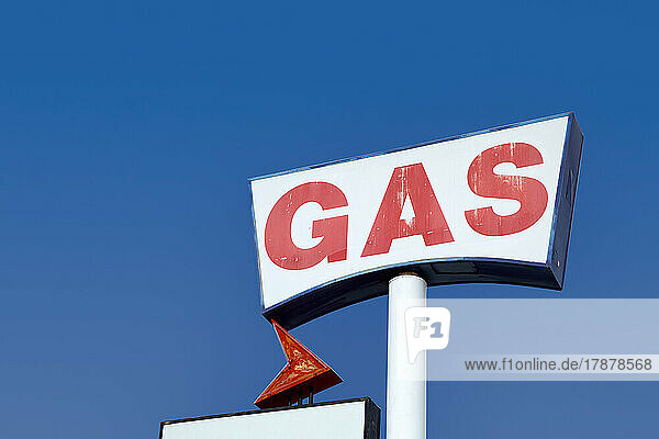 Low angle view of vintage gas station sign against sky