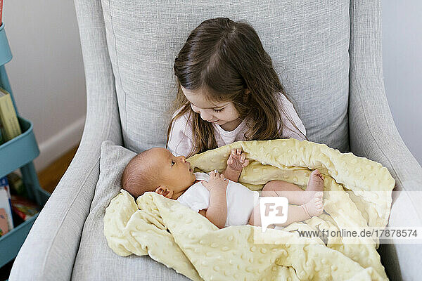 Girl (2-3) holding newborn baby brother (0-1 months)