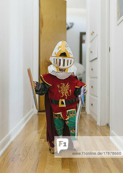 Toddler boy (2-3) in knight costume playing at home