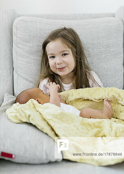 Girl (2-3) holding newborn baby brother (0-1 months)