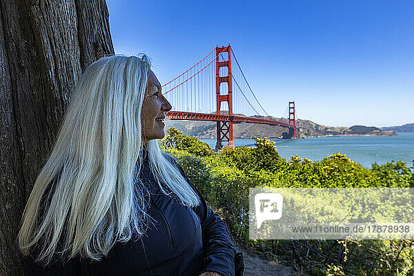 United States  California  San Francisco  Senior woman sitting in shade with view of Golden Gate Bridge