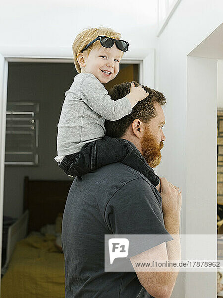 Father carrying son (2-3) on shoulders at home
