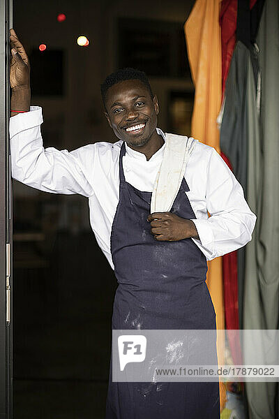 Porträt eines fröhlichen Restaurantbesitzers  der am Eingang steht