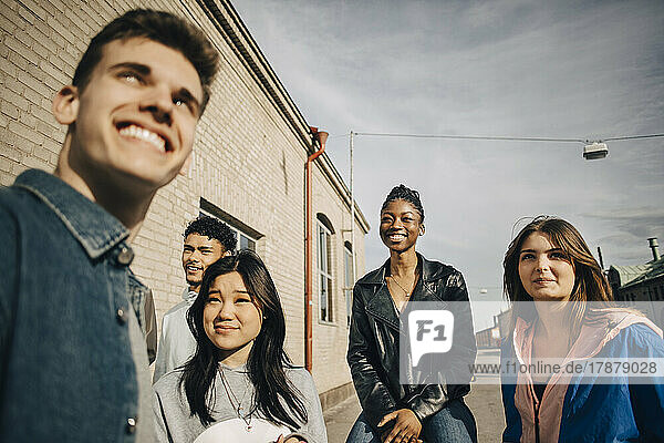 Lächelnde multirassische junge multirassische Freunde an einem sonnigen Tag