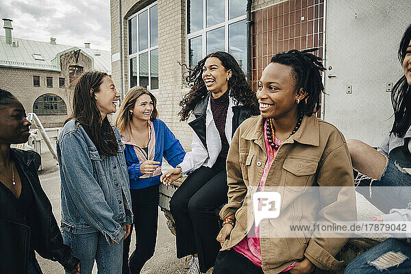 Glückliche multirassische junge Freunde unterhalten sich vor einem Gebäude