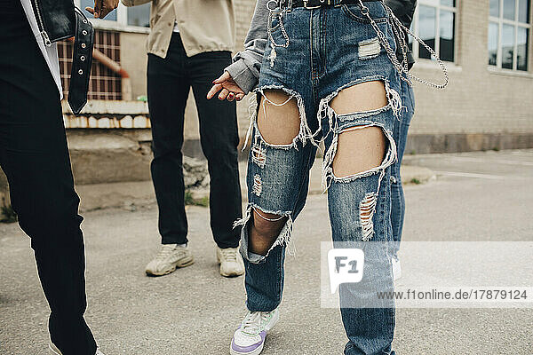 Tiefschnitt einer Frau in zerrissenen Jeans  die mit Freunden auf der Straße tanzt