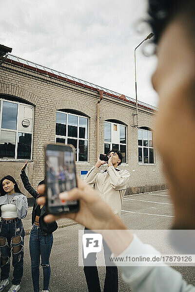Junger Mann fotografiert Freunde mit dem Handy auf der Straße in der Stadt