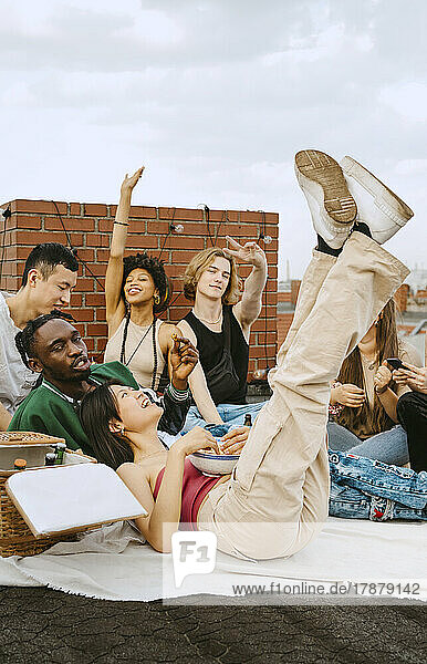 Glückliche männliche und weibliche Freunde genießen zusammen auf dem Dach