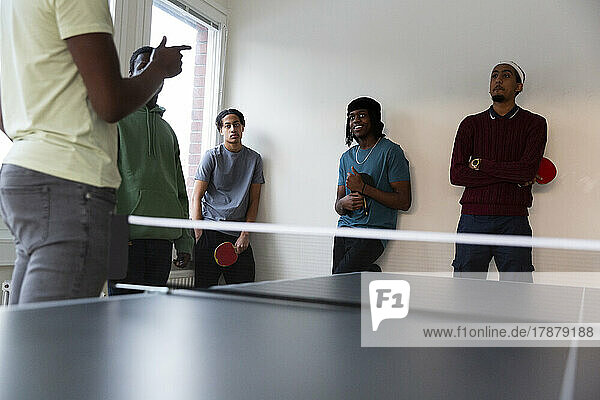 Students attending table tennis training given by instructor in games room