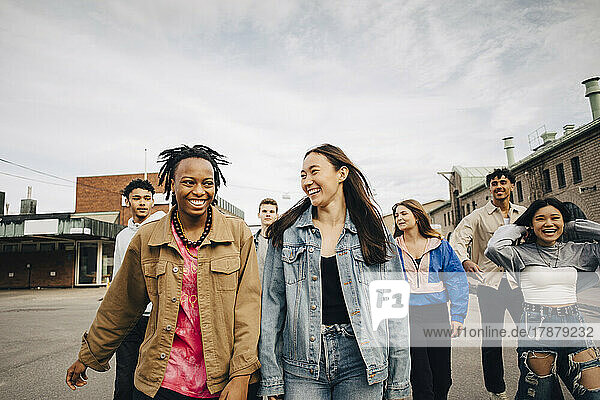 Glückliche multirassische junge Freunde  die auf einer Stadtstraße spazieren gehen